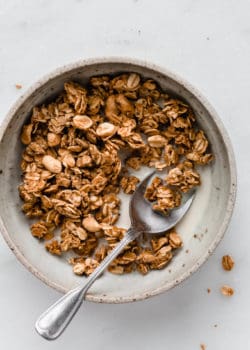 a bowl of peanut butter granola with milk and a spoon in it