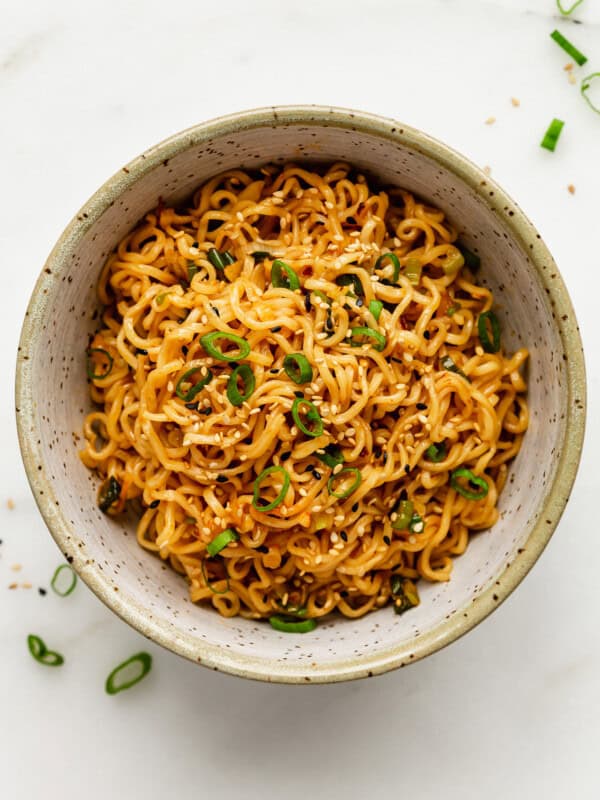 a bowl of spicy noodle topped with green onions