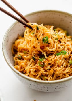 Chopsticks picking up ramen noodles from a bowl