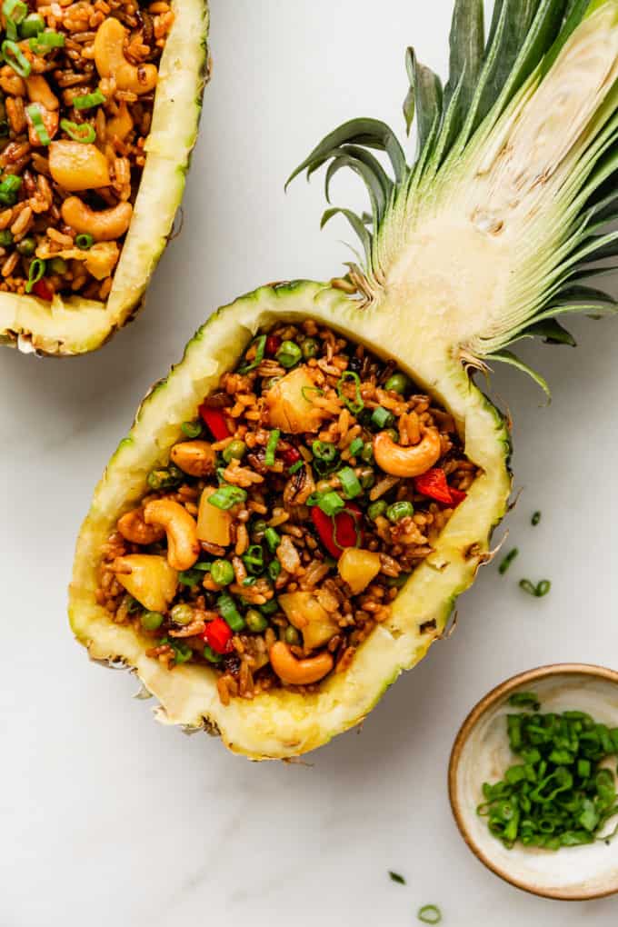 Thai pineapple fried rice in a pineapple bowl with green onions on top