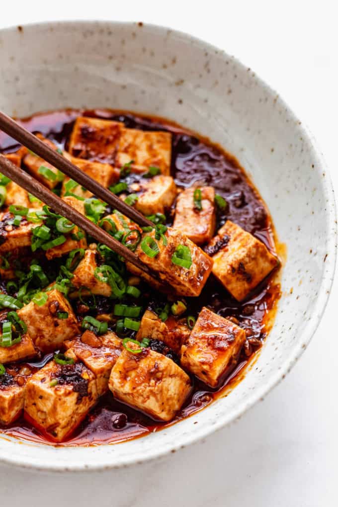 Chopsticks picking up a cube of mapo tofu