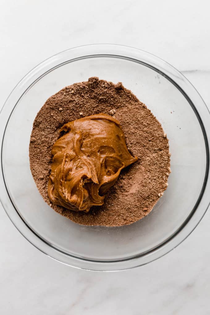 almond butter in a mixing bowl of dry ingredients for protein bars