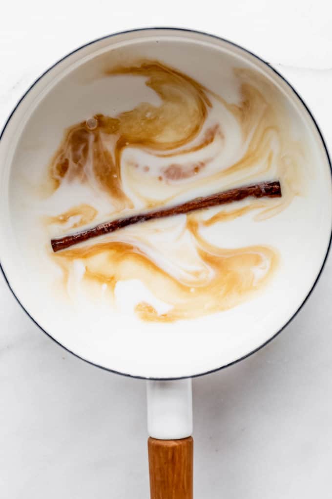 coconut milk, vanilla extract and a cinnamon stick in a white pot