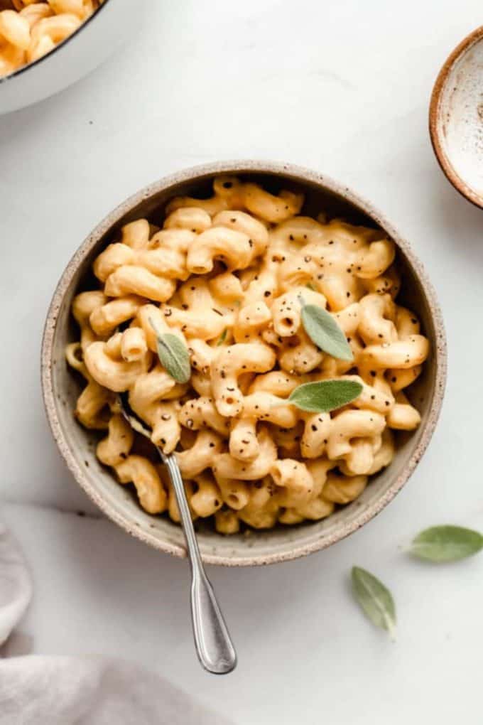 butternut squash mac and cheese in a ceramic bowl with a spoon