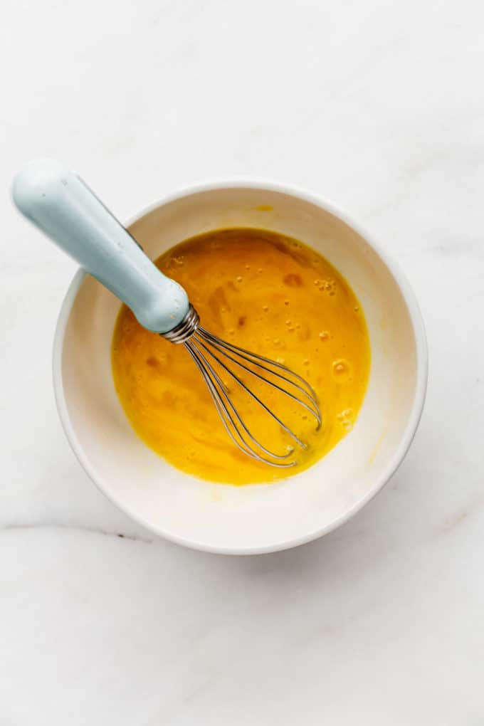 whisked eggs in a white bowl with a whisk