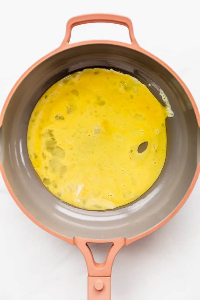 an uncooked omelette in a pink pan
