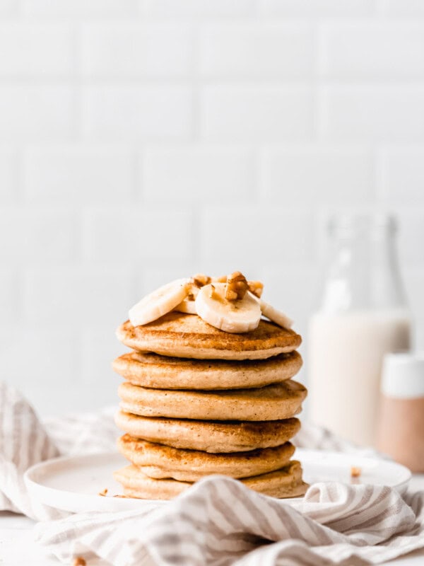 a stack of oat flour pancakes on a white plate on a striped napkin