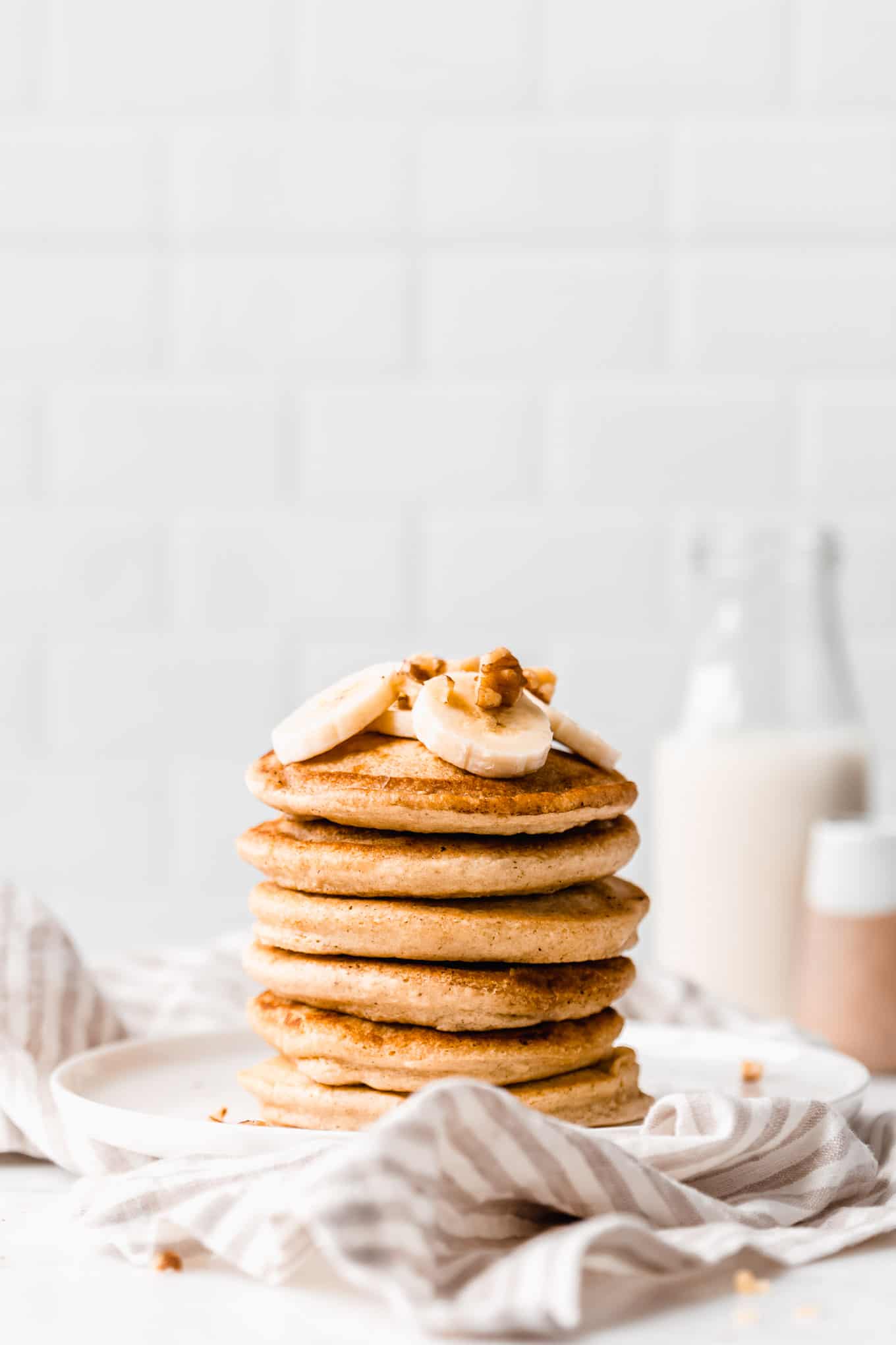 a stack of oat flour pancakes on a white plate on a striped napkin