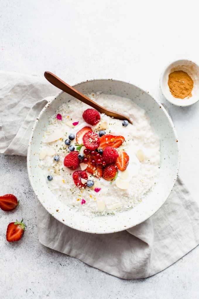 coconut rice pudding in a bowl on a grey napkin with cinnamon on the side