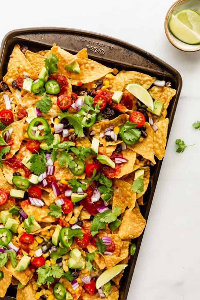 nachos topped with cilantro on a baking sheet