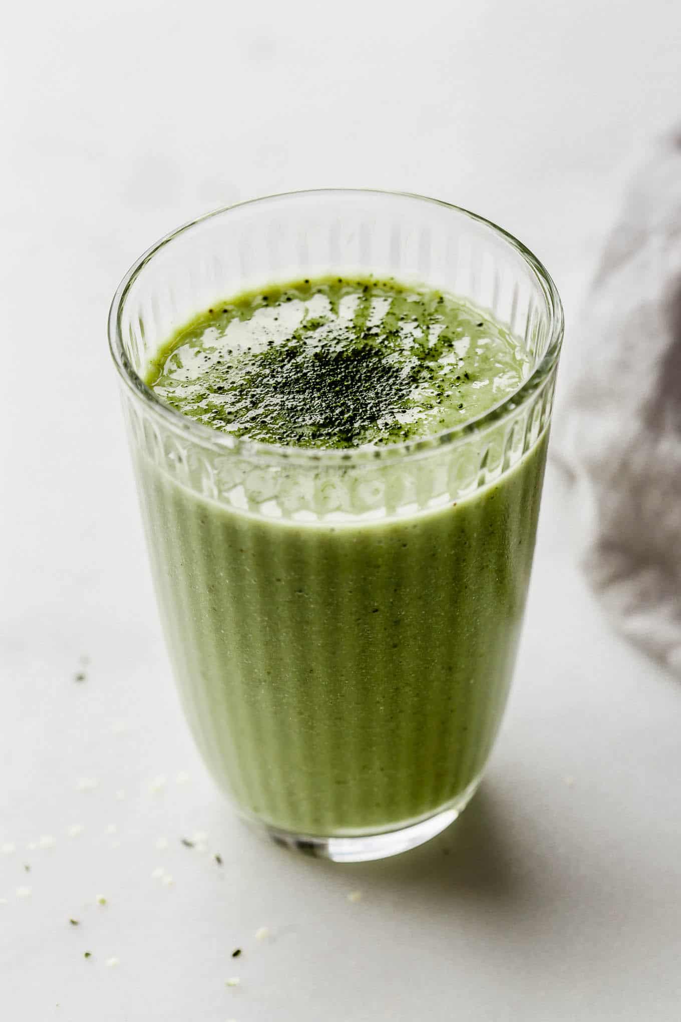 a glass of matcha smoothie topped with matcha powder