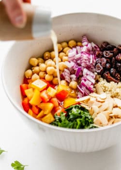 dressing being poured into a bowl of quinoa chickpea salad
