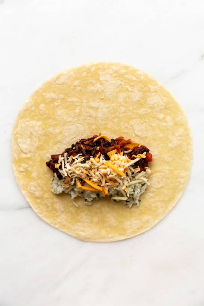 a tortilla with rice, beans and cheese on it