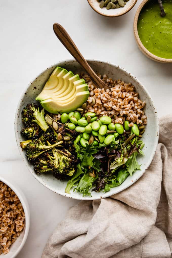 a green goddess bowl with a beige napkin and green sauce on the side