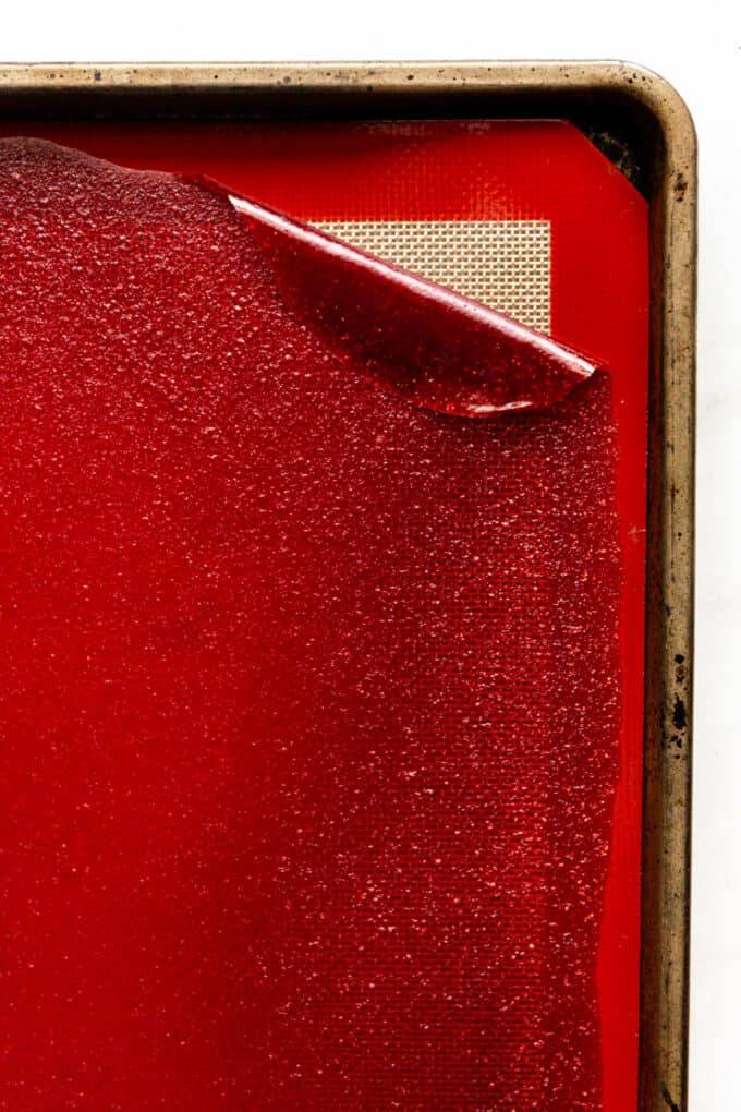 fruit leather being peeled off a baking sheet