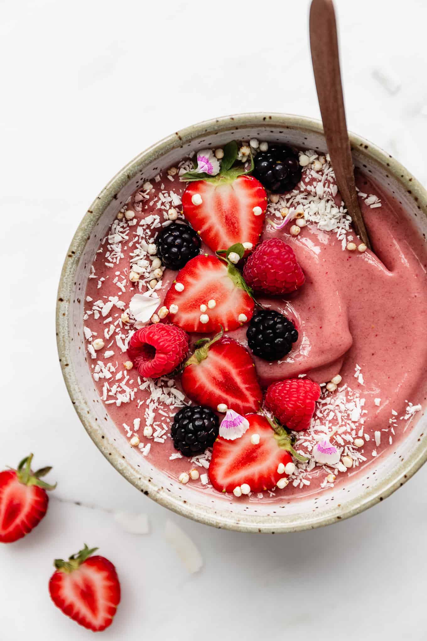 A strawberry smoothie bowl topped with strawberries and shredded coconut