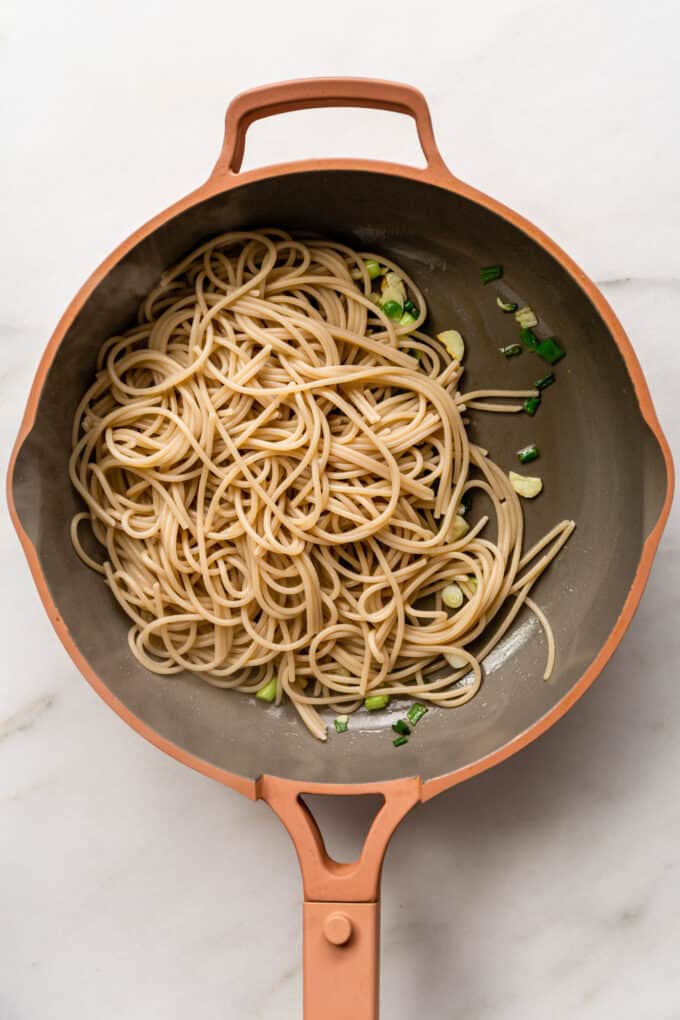 spaghetti, scallions and garlic in a pink pan