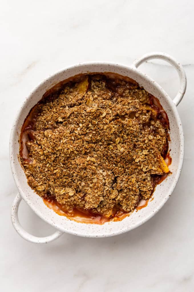 a peach crisp in a white speckled dish