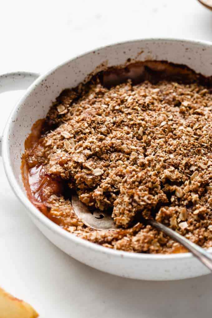 gluten-free peach crisp in a white speckled baking dish