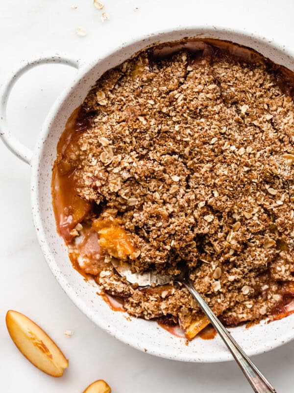 a gluten-free peach crisp in a dish with a serving spoon