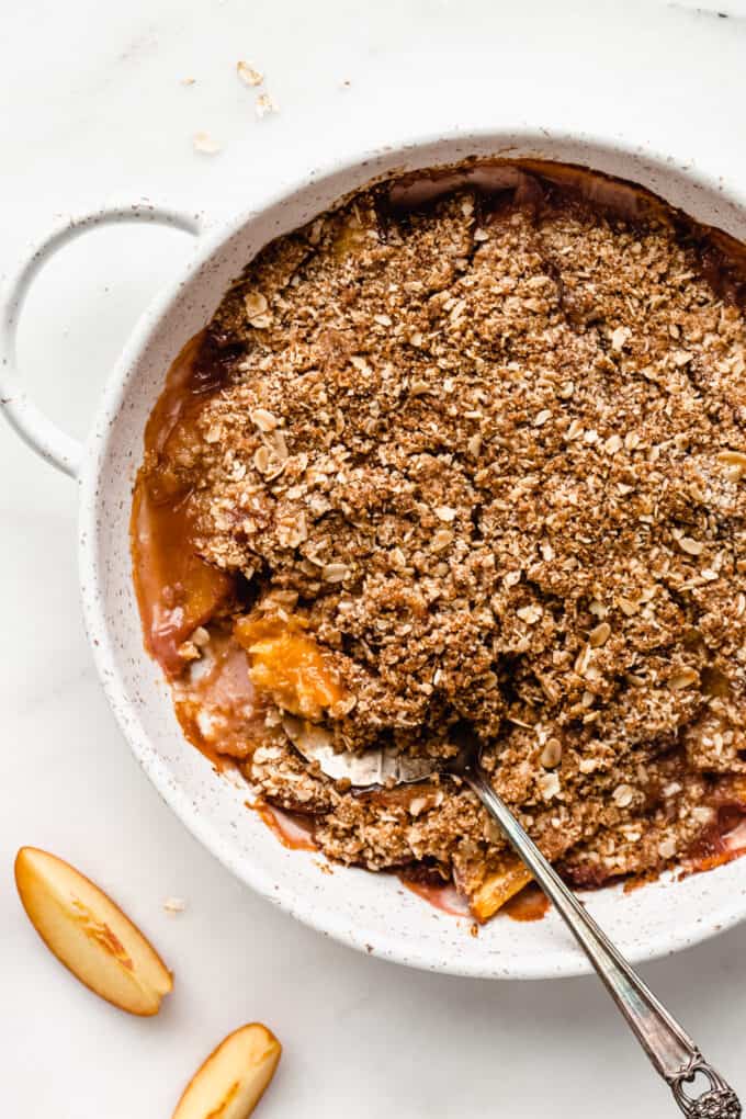 a gluten-free peach crisp in a dish with a serving spoon