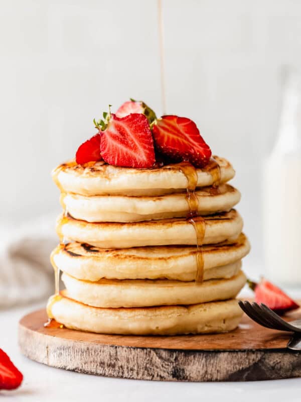 a stack of protein pancakes with maple syrup being poured on them