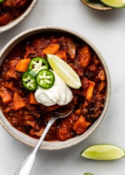 a bowl of sweet potato chili with lime, jalapeño and sour cream
