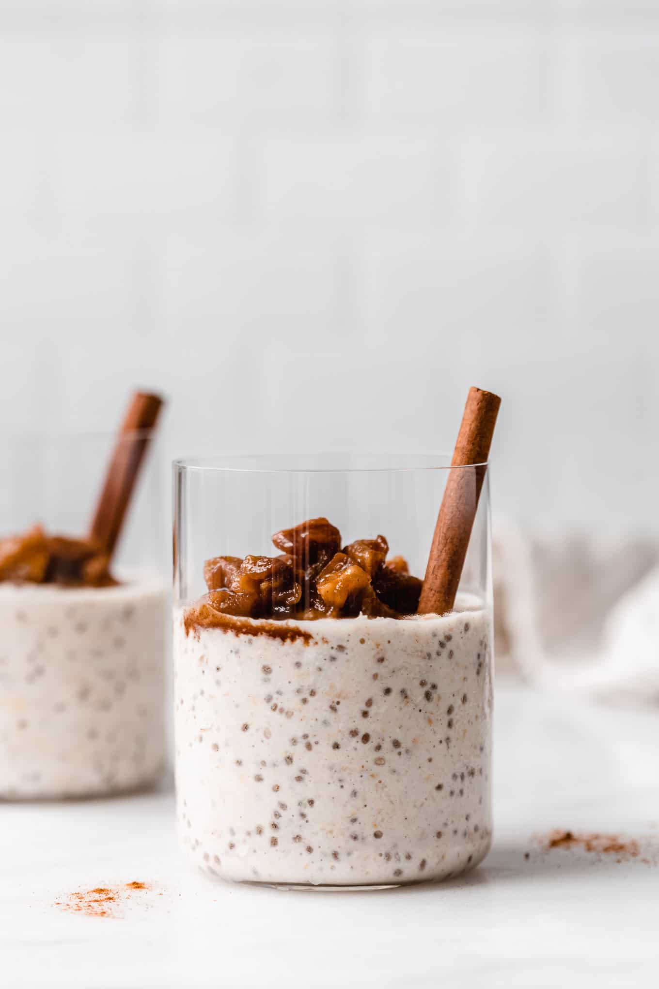 two cups of apple overnight oats with cinnamon sticks in them