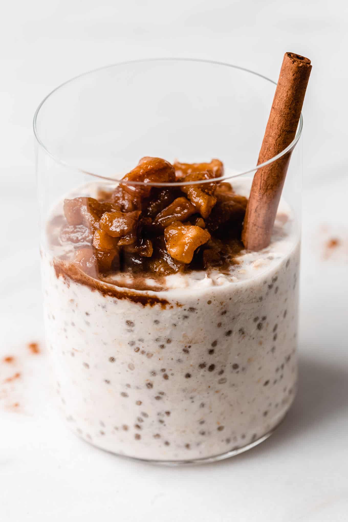 overnight oats topped with stewed apples in a white glass