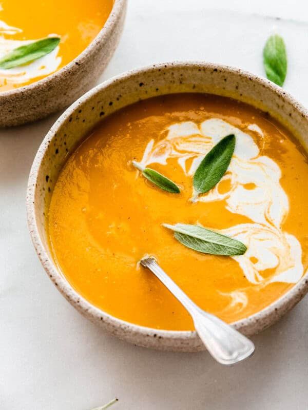 a bowl of butternut squash soup with apples with coconut milk on top
