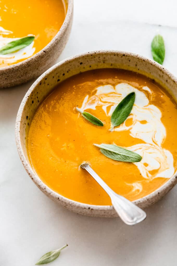 a bowl of butternut squash soup with apples with coconut milk on top