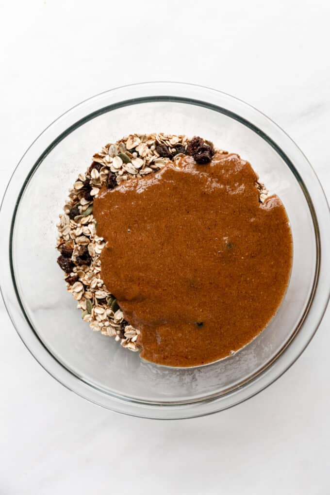oats, seeds and dried fruit in a bowl with nut butter poured over it