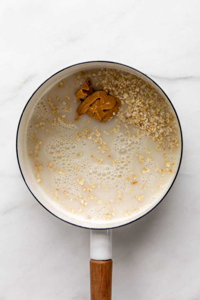 oats, almond milk and peanut butter in a white pot