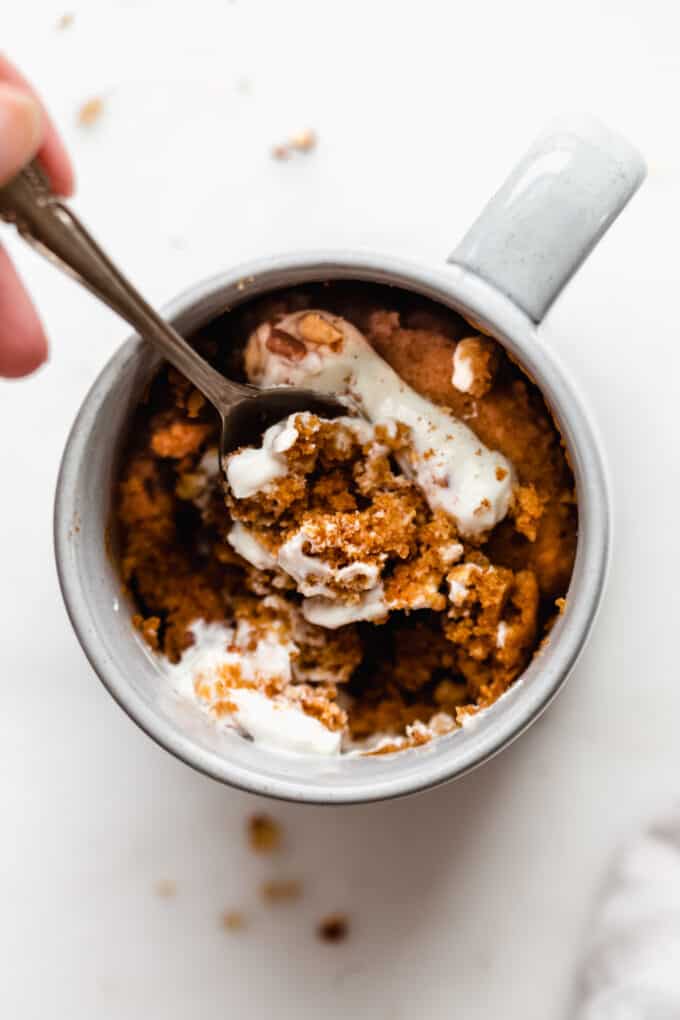 a spoon scooping pumpkin cake out of a mug