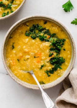 A bowl of red lentil soup topped with parsley