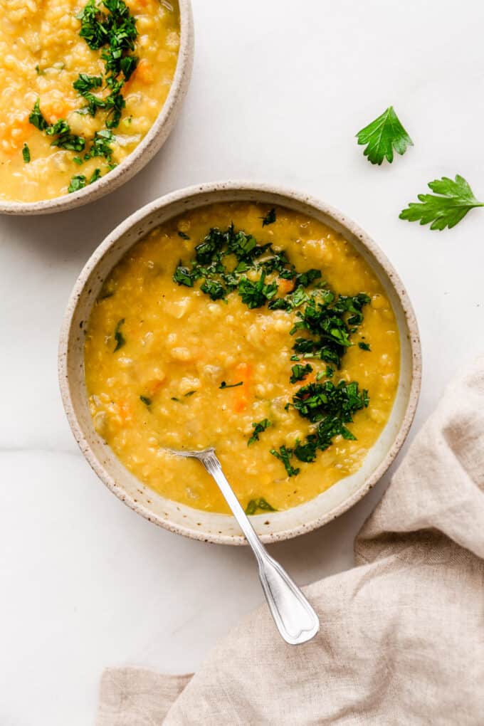 two bowls of red lentil soup with a beige napkin on the side
