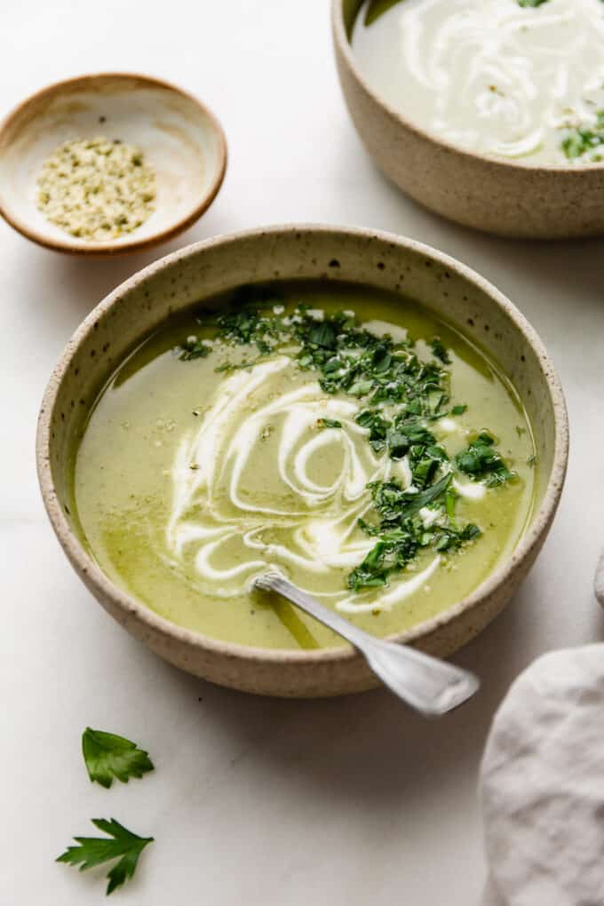 two bowls of broccoli potato soup with a small bowl of hemp seeds on the side