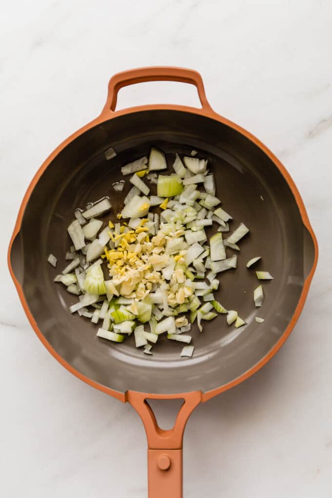 onions, garlic and ginger in a pink pan