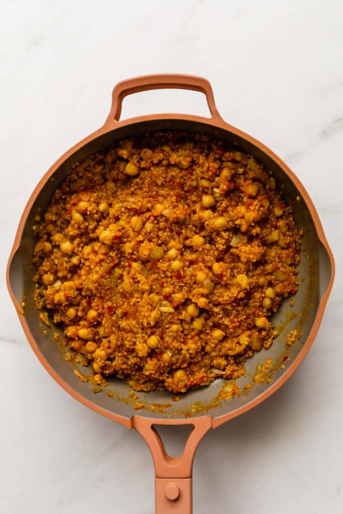 chickpeas and quinoa with tomato and spices in a pink pan