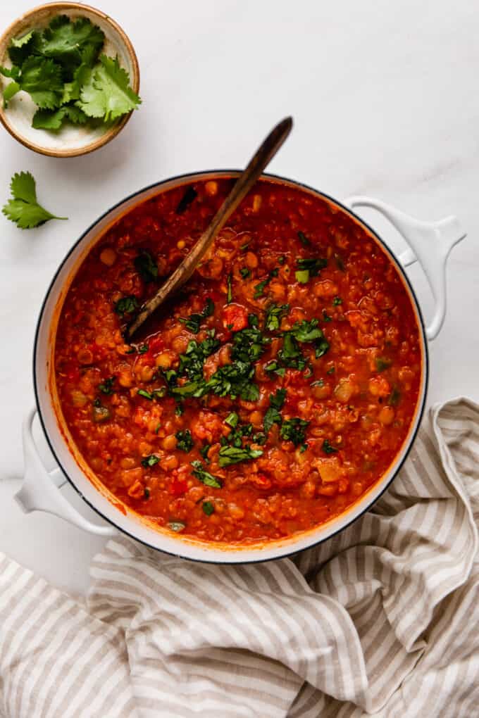 a pot of lentil chili with a beige striped napkin on the side