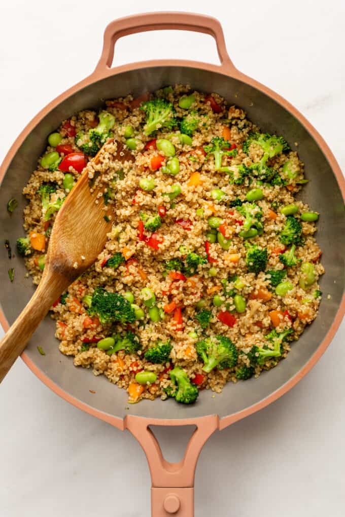 quinoa fried rice in a pink pan with a wood spatula