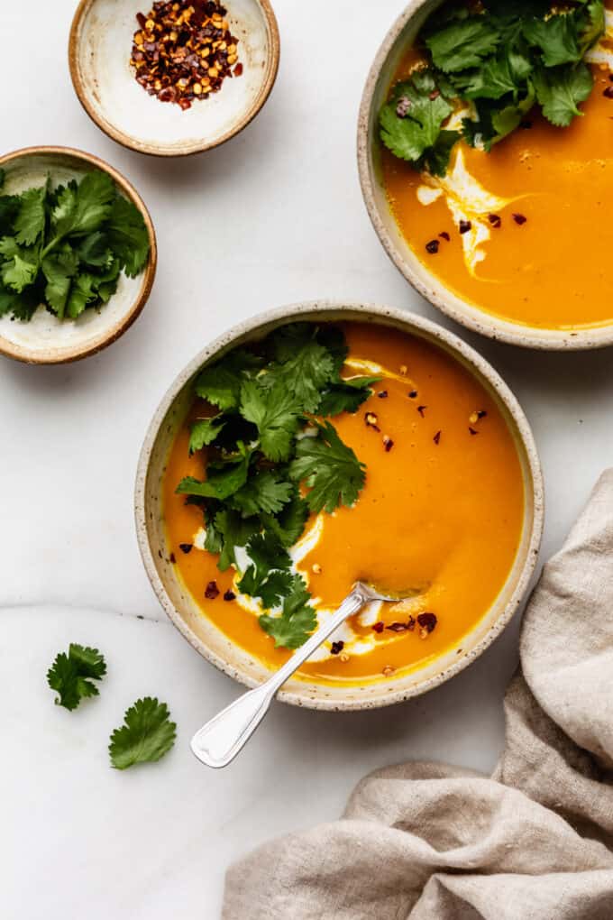two bowls of butternut squash sweet potato soup with a beige napkin on the side