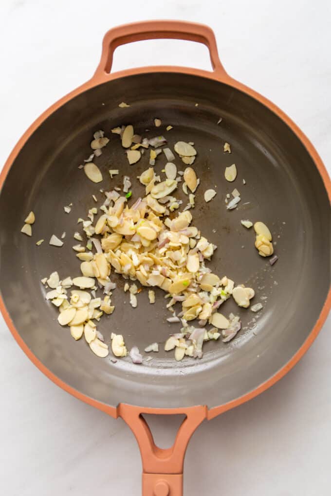 almonds, shallots and garlic in a pink pan