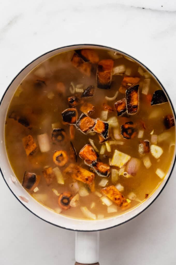 vegetable broth, sweet potatoes and carrots in a white pot