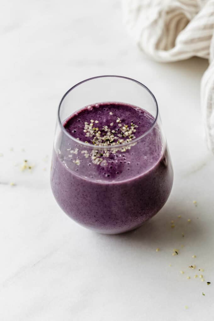 a glass of blueberry avocado smoothie on a marble board