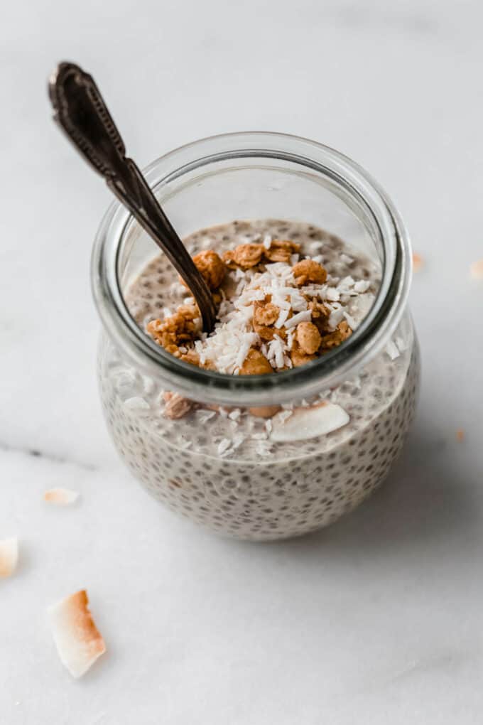 a jar of peanut butter chia pudding topped with shredded coconut and granola