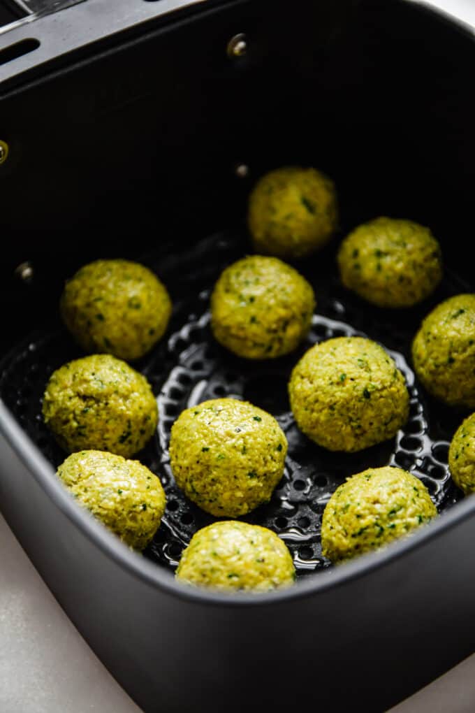 uncooked falafel in an air fryer basket