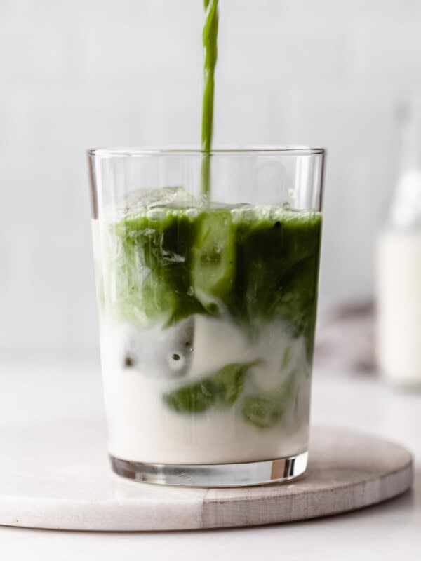 matcha being poured into a glass of oat milk