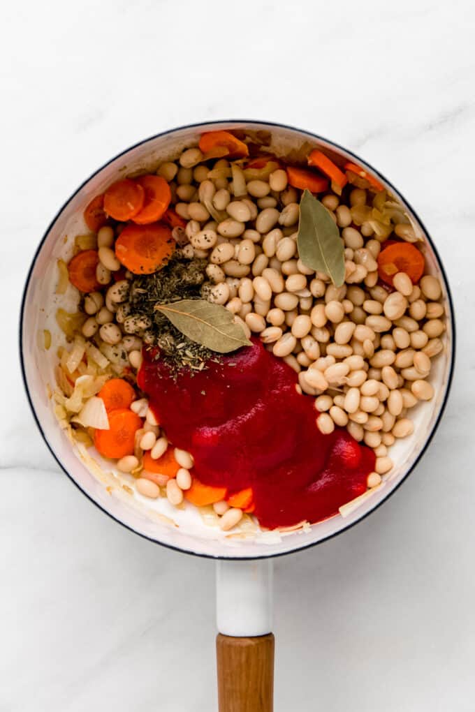 white beans, vegetables, herbs and crushed tomatoes in a white pot