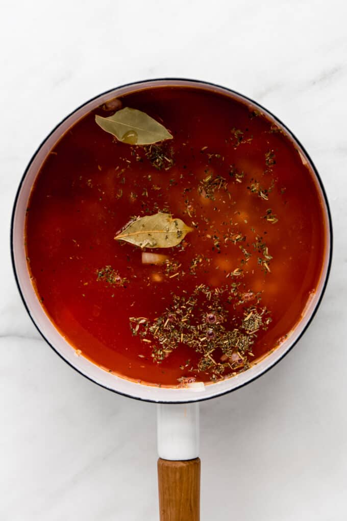 soup broth in a white pot with herbs